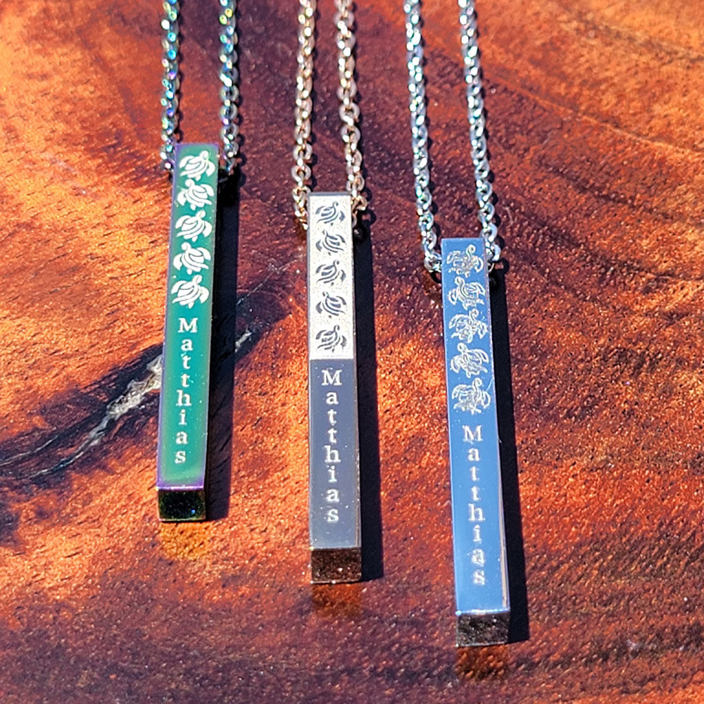 Vertical stainless steel bar pendants engraved with tribal honu designs and personalized text, symbolizing protection and strength