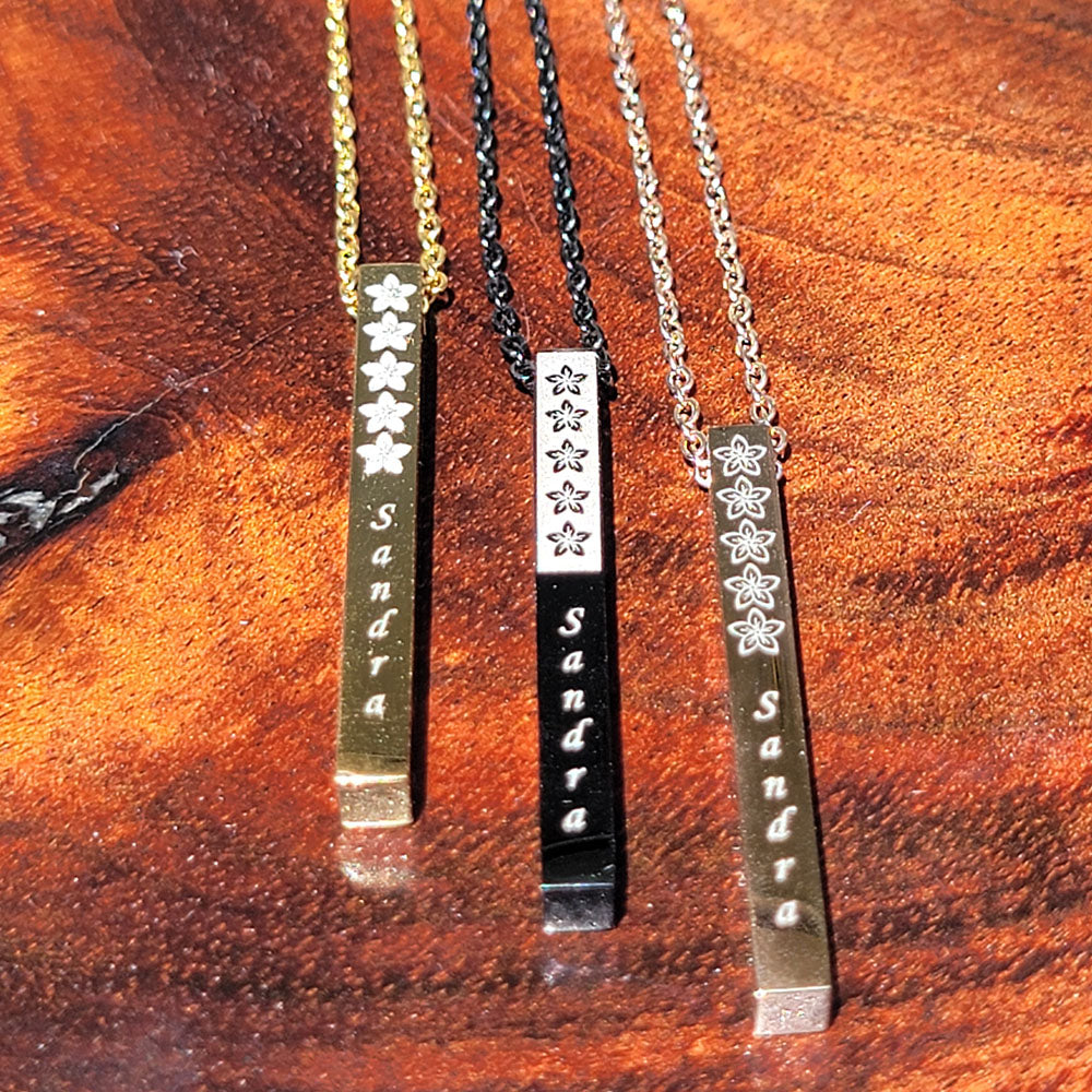 Vertical bar pendant in stainless steel with plumeria design and customizable engraving up to 11 characters